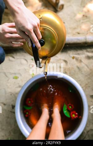 Bouilloire dorée à mise au point sélective versant de l'eau dans un bain aromatique du pied Banque D'Images