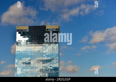 Bâtiment de grande hauteur avec façade en verre reflétant des nuages sombres et une lumière intense, Barcelone, Catalogne, Espagne Banque D'Images