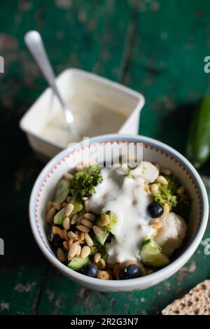 Salade au brocoli, chou-fleur, concombre, bleuets et pignons et sauce au yogourt au citron vert Banque D'Images