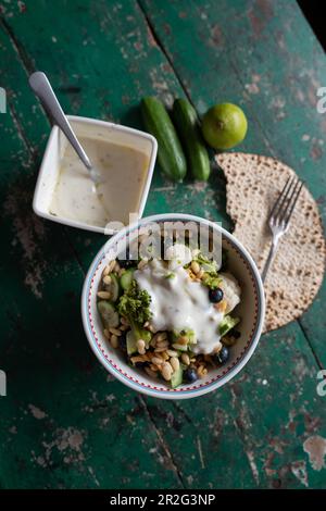 Salade au brocoli, chou-fleur, concombre, bleuets et pignons et sauce au yogourt au citron vert Banque D'Images