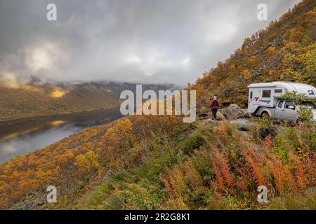 Personne debout devant une camionnette de camping dans un paysage d'automne, regardant le Gryllefjord, Senja, Norvège. Banque D'Images
