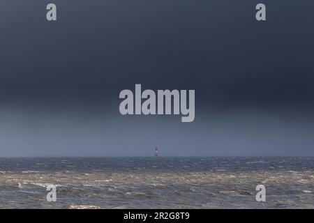 Vue sur la mer. nuages sombres. phare au loin. Wilhelmshaven, Jade Bay, Arngast, Basse-Saxe, Allemagne Banque D'Images