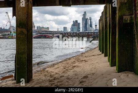 Londres. ROYAUME-UNI- 05.17.2023. Vue depuis le dessous de la jetée de la plage de la Tamise sur la rive sud de la Tamise avec vue sur les gratte-ciels de la CIT Banque D'Images