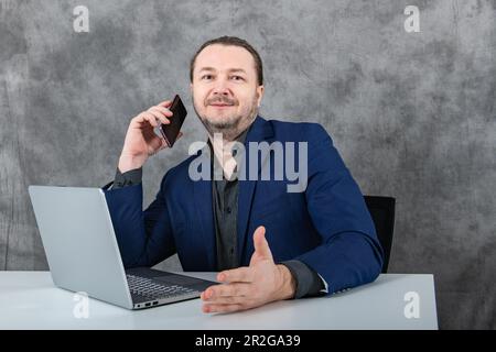 Homme d'affaires en colère parlant au téléphone à son ordinateur portable Banque D'Images