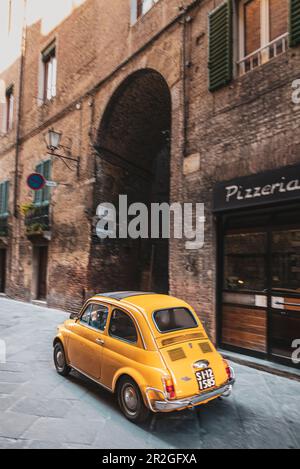 Vieux couple en Fiat 500 d'époque dans l'allée de la vieille ville, Sienne, Toscane, Italie, Europe Banque D'Images