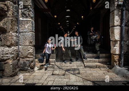 Jérusalem, Israël. 18th mai 2023. Une jeune fille palestinienne tient une fleur alors qu'elle passe devant les agents de la police frontalière israélienne dans la vieille ville fortifiée de Jérusalem pendant la marche du drapeau. Des dizaines de milliers de jeunes religieux-sionistes, hommes et femmes, ont défilé dans la capitale en faisant passer les drapeaux de l'étoile de David dans la vieille ville de Jérusalem, dans le cadre d'une marche controversée du drapeau, Marquant la réunification de la ville pendant la guerre des six jours et la prise par Israël du Mont du Temple et du mur occidental, les sites les plus saints du judaïsme. Crédit : SOPA Images Limited/Alamy Live News Banque D'Images