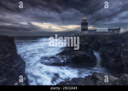 LHooks dirigez-vous vers le phare sur les falaises dans les mers de tempête. Après le coucher du soleil. Churchtown, Comté de Wexford, Ireland.tif Banque D'Images