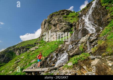 Alpinisme Femme marchant sur le pont au-dessus de la cascade, Floitental, Parc naturel des Alpes de Zillertal, Alpes de Zillertal, Tyrol, Autriche Banque D'Images