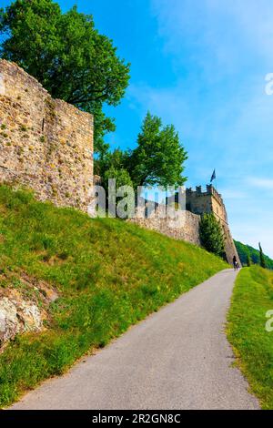 Femme marchant sur une passerelle vers un château et un vignoble lors d'une Sunny Journée d'été à Morcote, Tessin, Suisse. Banque D'Images