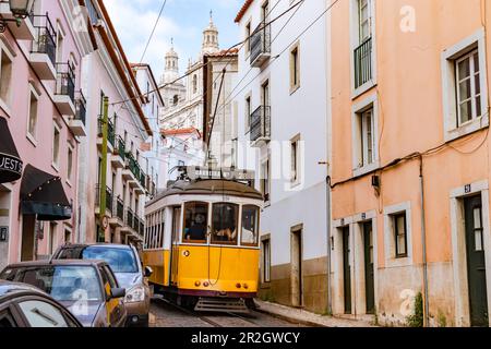 Le tramway 28E traverse une rue raide et étroite dans la vieille ville, Lisbonne, Portugal Banque D'Images