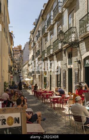 Une rue bordée de cafés et de places assises à l'extérieur à Lisbonne, Portugal Banque D'Images