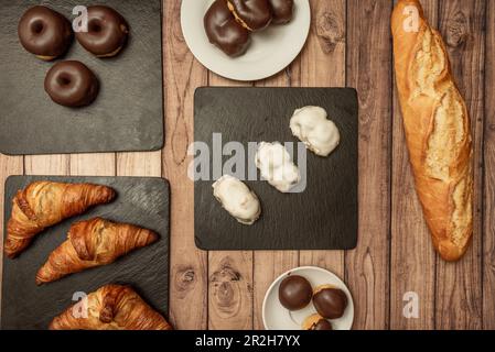 Ensemble de plats sucrés typiques et de desserts d'une boulangerie traditionnelle avec un pain et des croissants sur une table en bois similaire Banque D'Images