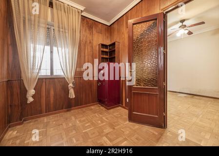 Une chambre vide avec un coffre-fort rouge et une porte en sapelli avec des fenêtres à la française et un parquet en chêne Banque D'Images