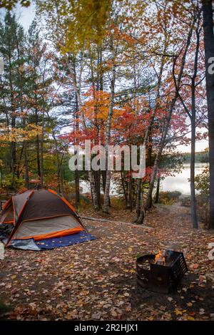 Coucher de soleil depuis un site de camping avec beau feuillage d'automne au bord d'un lac Banque D'Images