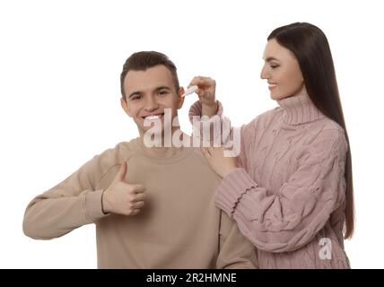 Une femme goutte des médicaments dans l'oreille de l'homme sur fond blanc Banque D'Images