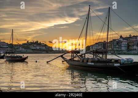 Les bateaux Rabelo chargés de barils de vin du port sur la rive du Douro au coucher du soleil, Porto, Portugal, Europe Banque D'Images