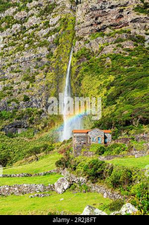 Vue panoramique de la cascade de Poco do Bacalhau tombant behiend une maison avec arc-en-ciel, Faja Grande, Lajes das Flores, Flores Island (Ilha das Flores) Banque D'Images