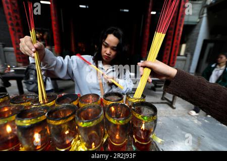 Le temple Thien Hau, le temple taoïste le plus célèbre de Cholon, femme priant avec des bâtonnets d'encens brûlants, Ho Chi Minh ville, Vietnam, Indochine Banque D'Images