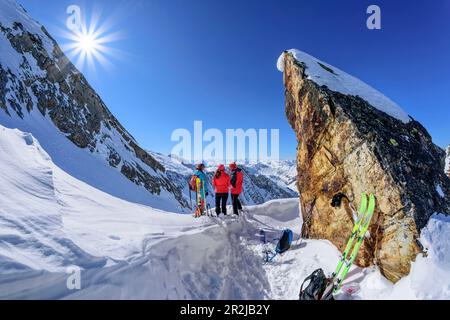 Trois personnes en visite de ski se tiennent sous la tour de roche et regardent les Alpes de Zillertal, Höllensteinkar, la vallée de Tux, les Alpes de Zillertal, Tyrol, Autriche Banque D'Images