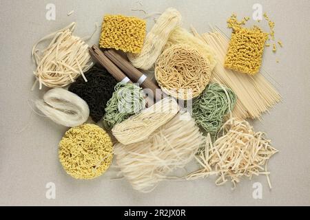 Divers types de nouilles asiatiques brutes, Soba, Ramen, Ramyeon, Misua, Sarcelle à motif de kway, nouilles aux œufs de légumes, Domen. Vue de dessus sur la table de crème Banque D'Images