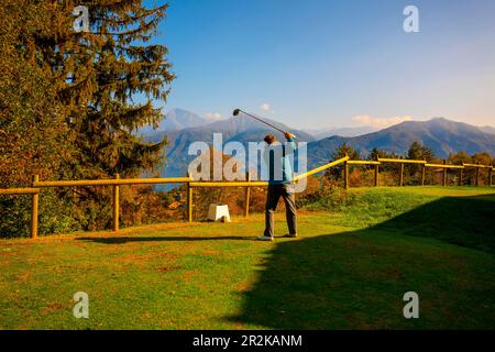 Golfeur Tearing off avec son chauffeur sur le terrain de golf Menaggio avec vue sur la montagne en automne dans Lombardie, Italie. Banque D'Images