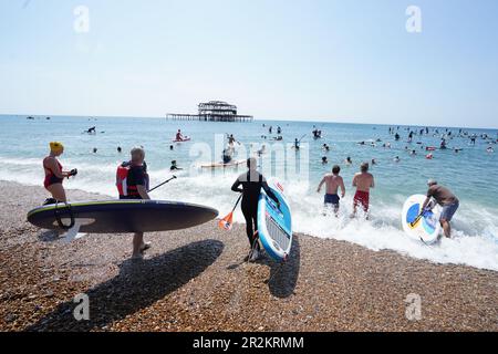 Les manifestants s'embarquent dans l'eau tandis que Surfers Against Sewater tient une manifestation de paddle-out à Brighton West Pier dans East Sussex, demandant la fin des rejets d'eaux usées dans les eaux de baignade britanniques d'ici 2030. Date de la photo: Samedi 20 mai 2023. Banque D'Images