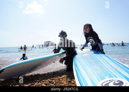 Les manifestants s'embarquent dans l'eau tandis que Surfers Against Sewater tient une manifestation de paddle-out à Brighton West Pier dans East Sussex, demandant la fin des rejets d'eaux usées dans les eaux de baignade britanniques d'ici 2030. Date de la photo: Samedi 20 mai 2023. Banque D'Images