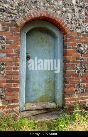 Porte en bois peint dans un vieux bâtiment en silex et briques Banque D'Images