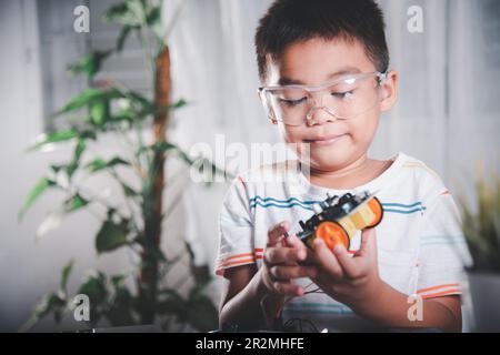 Petit enfant essayant d'assembler la roue de construction au jouet de voiture Banque D'Images