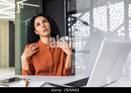 La chaleur dans le bureau, la climatisation est cassée, la travailleuse essaie de se refroidir en agitant ses mains, la femme d'affaires est surfatiguée du manque d'air frais sur le lieu de travail à l'intérieur du bureau. Banque D'Images