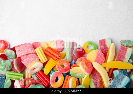 Beaucoup de savoureuses bonbons colorés en gelée sur une table blanche, à plat. Espace pour le texte Banque D'Images