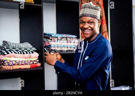 Photo d'un homme africain élégant posé devant un porte-vêtements Banque D'Images