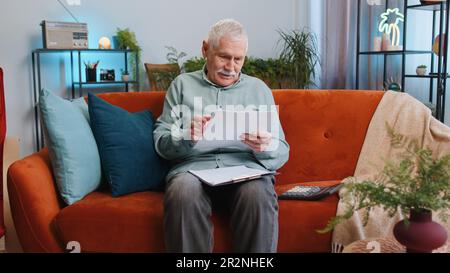 Un homme grand-père heureux travaille avec des documents de la maison, analyse de l'information, lire des documents d'affaires préparer un rapport financier à la maison. Un homme âgé gagnant choqué par la victoire soudaine bonne nouvelle de succès Banque D'Images