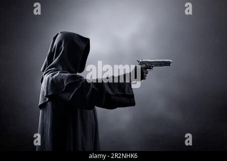 Moine à capuchon avec un pistolet dans l'obscurité Banque D'Images