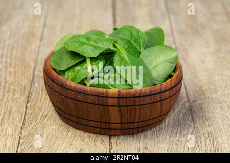 Feuilles d'épinards fraîches dans un bol sur fond de bois Banque D'Images