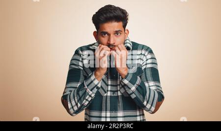 L'Indien déprimé stressé terrifié au sujet des problèmes de danger, la phobie de souffrance, le désordre d'anxiété, exprime la peur, agitant non, insécurité, stress, panique. Un type hindou isolé sur fond beige studio Banque D'Images