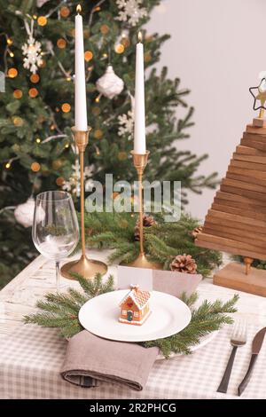 Cadre festif avec vaisselle, couverts et porte-cartes maison en pain d'épice pour un dîner de Noël sur une table en bois blanc Banque D'Images