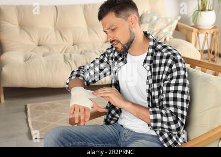 Homme appliquant un bandage médical sur la main à la maison Banque D'Images