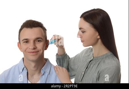 Une femme goutte des médicaments dans l'oreille de l'homme sur fond blanc Banque D'Images