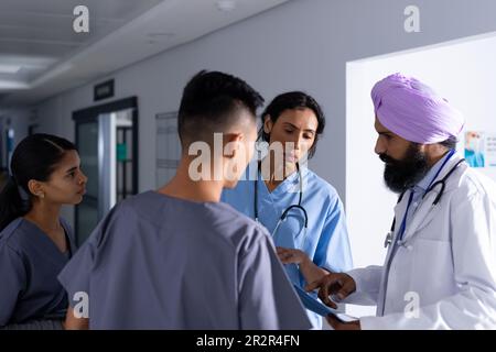 Divers médecins hommes et femmes discutant de rayons X dans le couloir de l'hôpital Banque D'Images