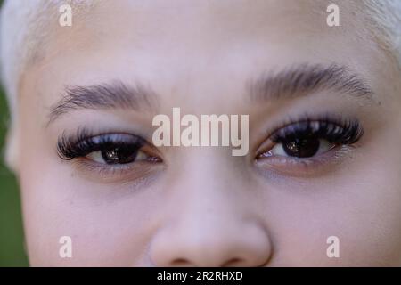 Portrait non modifié gros plan des yeux d'une femme biraciale souriante avec des cheveux courts blanchis. Détente, temps libre et style de vie. Banque D'Images