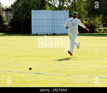 Club cricket, Warwick, Angleterre, Royaume-Uni. Un péroné qui poursuit la balle jusqu'à la limite. Banque D'Images