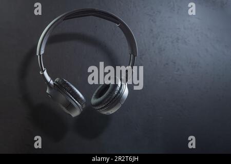 Casque sans fil de grande taille sur fond sombre. Casque noir, lévitation. Copier l'espace Banque D'Images