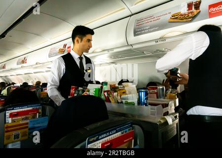 Agents de bord masculins servant repas et boissons aux passagers dans une cabine d'avion Airbus A 320 exploité par Turkish Pegasus Airlines Banque D'Images