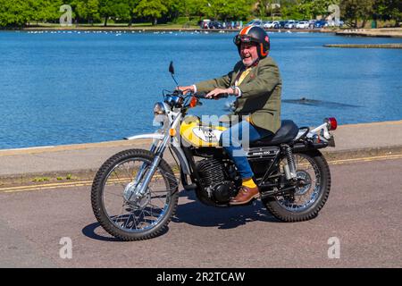 Poole, Dorset Royaume-Uni. 21 mai 2023 Bournemouth et Poole Distinguished Gentleman’s Ride est un événement annuel, l’un des nombreux dans le monde, qui vise à recueillir des fonds et à sensibiliser la population à la santé des hommes. Dans le cadre de leur balade, des centaines de motos, beaucoup vintage, traversent Poole Park sur leur chemin vers Bournemouth avec beaucoup de leurs coureurs habillés de manière appropriée, dans des cravates de style rétro, des moustaches et des tweeds par une belle journée ensoleillée. Homme portant veste et cravate s'amuser à rouler jaune Yamaha Enduro DT 400 moto. Crédit : Carolyn Jenkins/Alamy Live News Banque D'Images