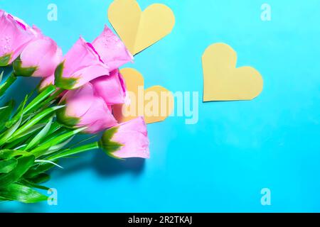Bouquet de roses roses et coeurs jaunes sur fond bleu Banque D'Images