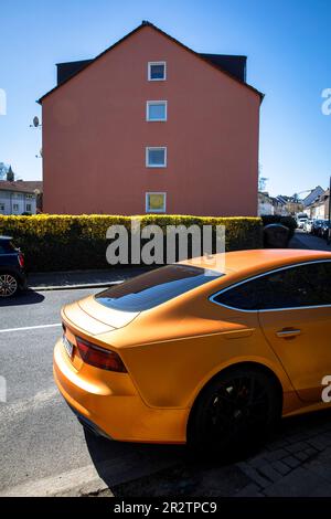 Une Audi A5 Sportback orange est garée en face d'une maison rouge dans le quartier de Niehl à Cologne, en Allemagne. ein orangefarbener Audi A5 Sportback stht vo Banque D'Images