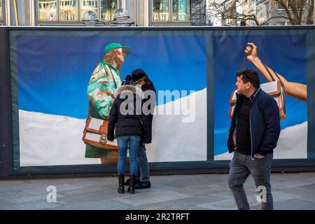 Un couple se tient devant une clôture de construction avec des affiches publicitaires près de la cathédrale, Cologne, Allemagne. ein Paar steht vor einem Bauzaun mit W Banque D'Images