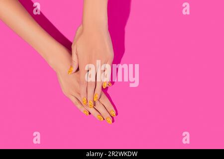 Des mains de femmes soignées avec un motif à ongles tendance sur fond rose Banque D'Images