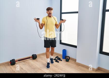 Homme arabe avec formation de barbe avec corde de saut célébrant fou et stupéfié pour le succès avec les yeux ouverts hurlant excitant. Banque D'Images